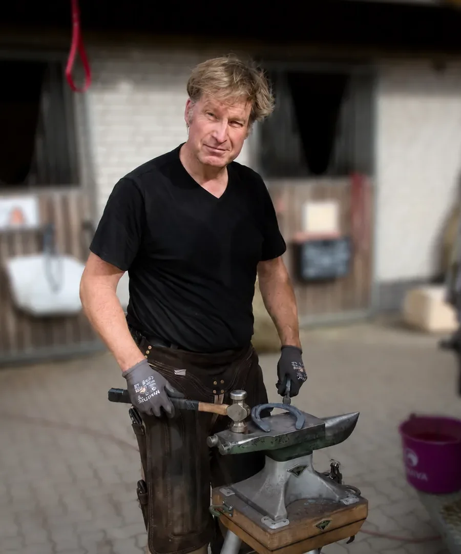 Björn Kohrs, Hufschmied, mit Amboss und Hammer im Stallhof